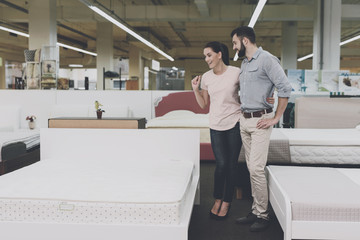 A man and a woman choose a bed in the store. I think they chose one