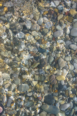 sea pebble beach with multicoloured stones, waves with foam