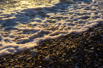 sea pebble beach with multicoloured stones, waves with foam