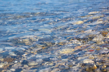 sea pebble beach with multicoloured stones, waves with foam