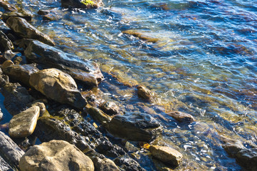 rocky sea shore with pebble beach, waves with foam