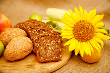 Still, the composition of different kinds of apples, pears, corn, sunflower and bread. Autumn harvest of fruits and vegetables piled on the table. Apples of various colors, red, green, yellow fruit.