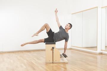 Naklejka premium Pilates instructor performing fitness exercise on chair equipment