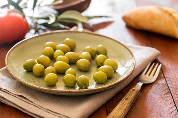 Fresh green olives on the rustic plate