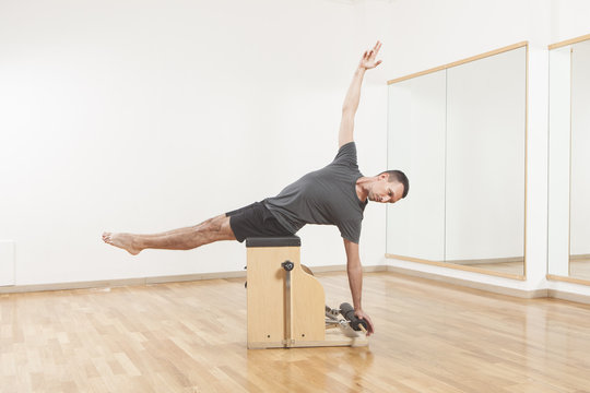 Pilates instructor performing fitness exercise on chair equipment