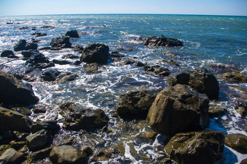 rocky sea shore with pebble beach, waves with foam