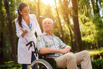 Doctor talking to old man in wheelchair