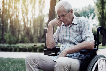 Sad old man in a wheelchair on the park