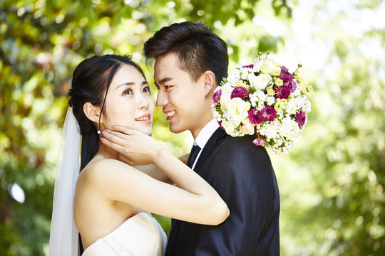 closeup outdoor portrait of a loving asian newly-wed couple