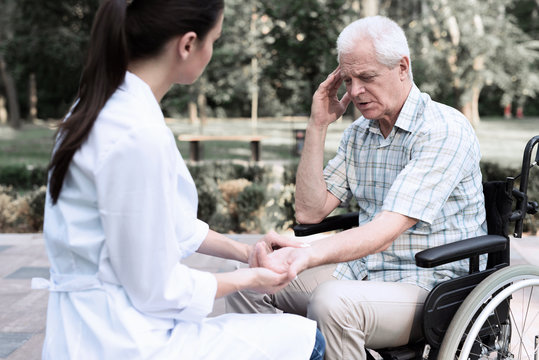 An elderly man in a wheelchair complains of a headache to a doctor