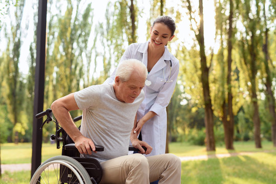 Care helps cure all ailments. The doctor helps the patient to get up from the wheelchair