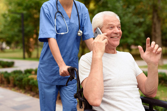 Happy old man in a wheelchair talking on a mobile phone