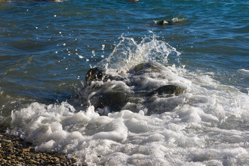 rocky sea shore with pebble beach, waves with foam