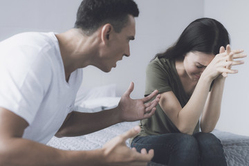 A woman is crying with her head in her hands, while her man angrily shouts at her waving his arms