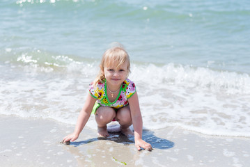 A child, a little girl playing fun on the seashore in the summer.