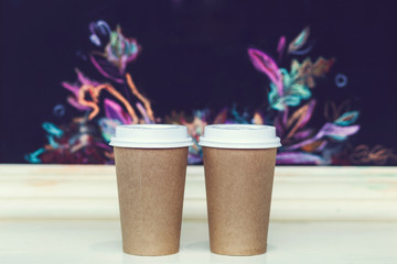 Two carton paper cups with cap at the bar with autumn pattern. Empty space for logo, text, sign