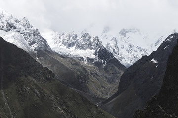 Fototapeta na wymiar Snow mountain peaks of Caucasus mountains in cold cloudy weather, Elbrus Region. Main caucasian ridge