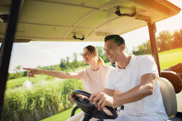 Couple riding a white golf cart on the golf course © Vadym Huzhva