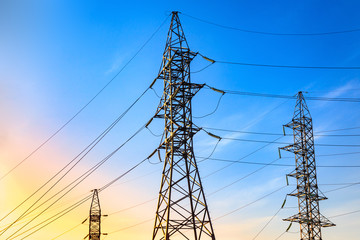 Pylons and transmission power lines on the blue sky background.