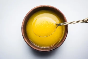 Plexiglas foto achterwand Ghee or clarified butter close up in wooden bowl and silver spoon, selective focus   © StockImageFactory