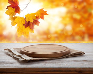 Pizza board with tablecloth on wooden table and autumn background - can used for display or montage your products
