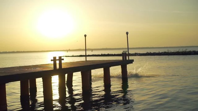 Silhouette man somersault backs jumping sea pier sunset rapid slow motion 