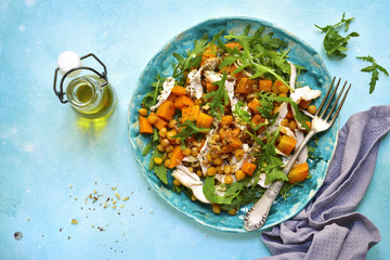 Warm autumn salad with pumpkin,chickpea,arugula and grilled chicken.Top view.