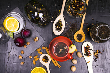 Teas in cans and wooden spoons surrounded by fruit and nut