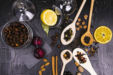 Teas in cans and wooden spoons surrounded by fruit and nut