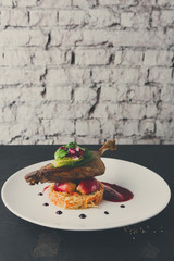 Restaurant meals. Duck confit with vegetables on black backgroun