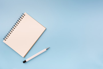 top view of blank notebook and pen on light blue background with copy space. memo and planning concept.