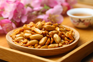Spicy peanuts in wooden plate on bamboo plate