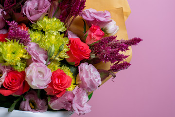 A beautiful bouquet of pink eustoms, a yellow chrysanthemum, a red and pink rose, on a pink background