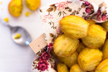 French desserts that have the form of a shell. Madeleine close-up in a beautiful wooden box, with a floral patterned napkin.