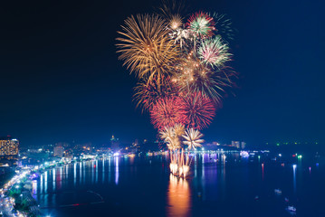 Fototapeta premium Fireworks over the sea beach with blue twilight sky background and city view