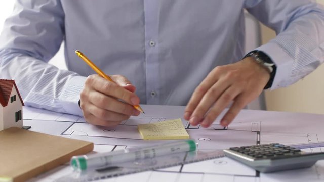 architect with blueprint and stickers taking notes