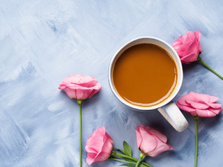 Mug of coffee and pink flowers on blue background. Flat lay festive mother valentine day greeting card