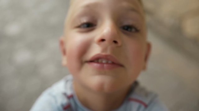 A little boy with beautiful dark eyes and large eyelids kisses the camera's objective. Beautiful little boy