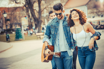 Group of friends laughing and walking at the city downtown.They embrace each other and smiling.