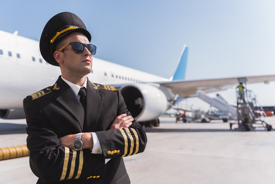 Confident male pilot standing outside