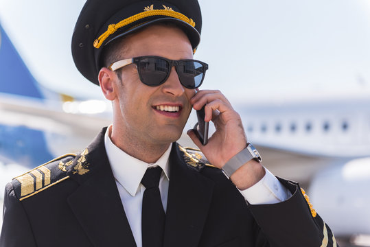 Joyous smiling pilot speaking on phone