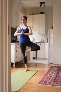 Full Length Of Woman Doing Yoga In Kitchen