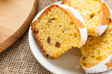 homemade traditional fruit cake slices at white plate decorated with raisins on wooden table top view