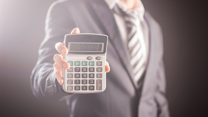 Businessman with calculator showing reports isolated on dark background