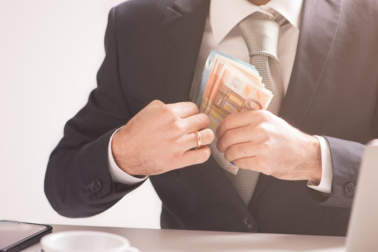 Money in pocket, businessman putting euro banknotes in suit pocket, bribe and corrupution concept.