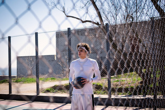 Portrait of a basketball player standing with ball near gread on basketball court