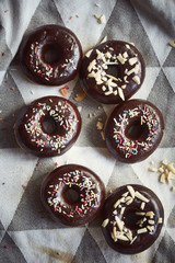 Schokoladen Donuts frisch gebacken mit Streuseln, Mandeln auf Tischtuch von oben