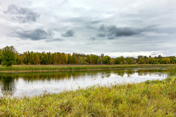 Autumn landscape. River and forest against the background of a cloudy sky