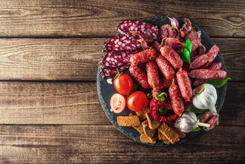 Food tray with delicious salami, pieces of sliced ham, sausage, tomatoes, salad and vegetable.