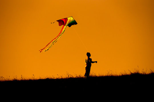 Silhouette of people flying a kite top of mountain sunset evoke emotion happy memories.  Doi Mon Jong Chiang Mai Thailand.